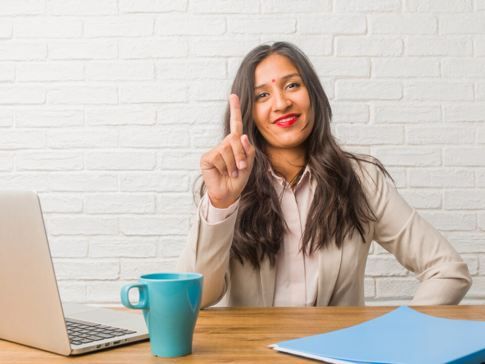 Woman holding up one finger at a computer
